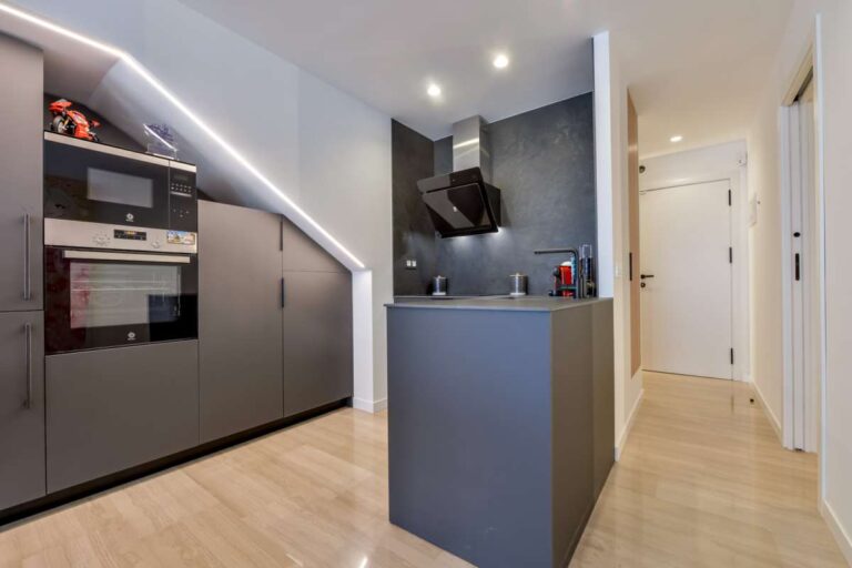 Modern kitchen inside a luxury frontline beach duplex in Mascarat, Altea with island, integrated oven, tall cabinetry and wood-effect flooring