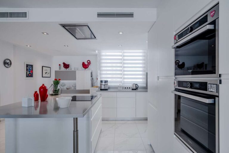 Modern kitchen inside a renovated apartment by Arenal-Bol Beach in Calpe with island, built-in appliances and bright white finish