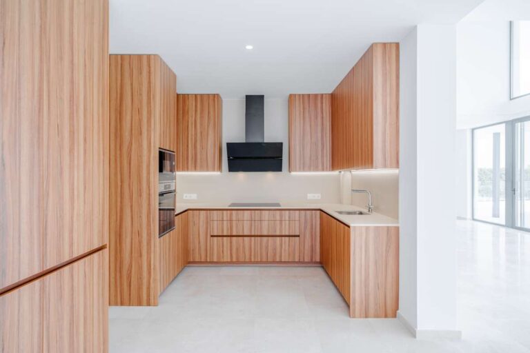 Modern kitchen inside a second-line sea villa in La Calalga, Calpe with wood cabinetry, integrated appliances and bright contemporary finish
