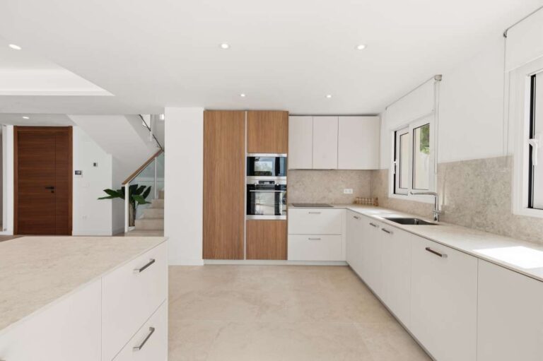 Modern kitchen inside a villa in Altea Hills with white cabinetry, integrated appliances, large worktops and bright neutral finish