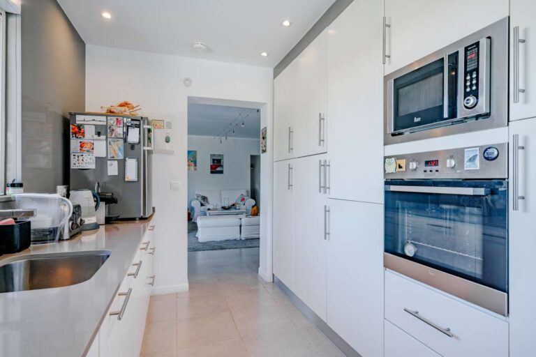 Modern kitchen inside a villa in Calpe with white cabinetry, built-in oven, microwave and bright interior finish