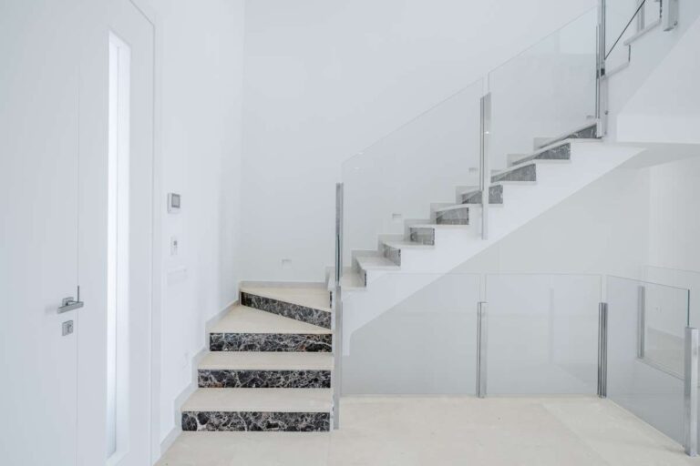 Modern staircase inside a second-line sea villa in La Calalga, Calpe with glass balustrade, bright white walls and contemporary interior design