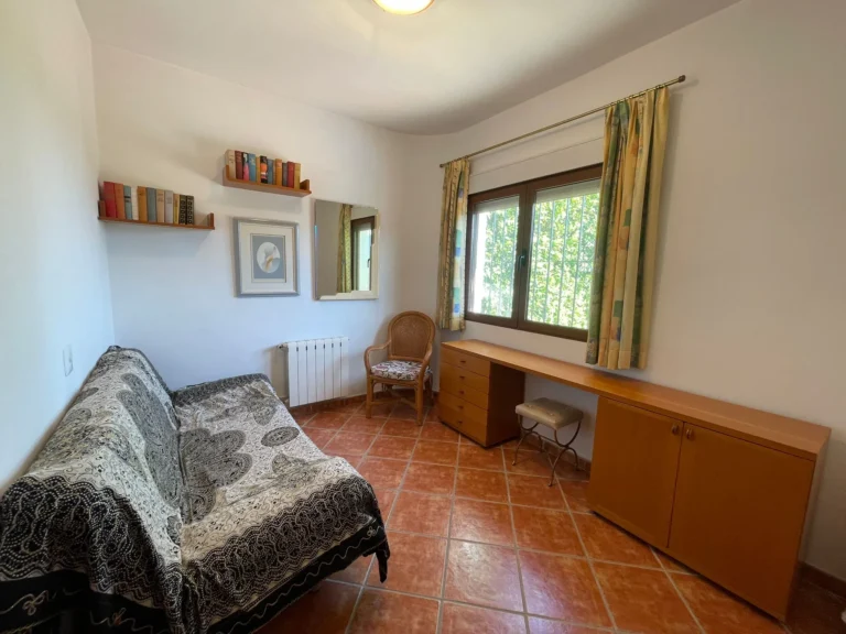 Office room with built-in desk, sofa, radiator, and natural light inside a villa in Calpe.