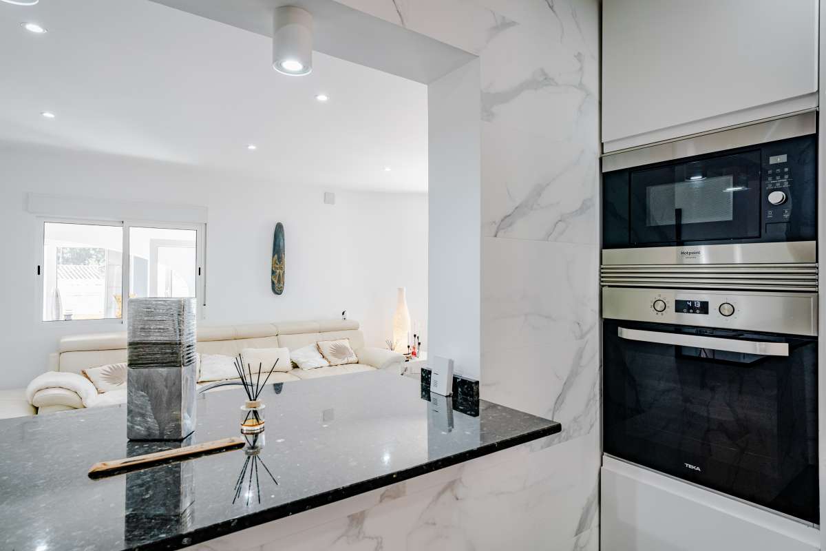 Open kitchen detail with breakfast bar and integrated oven inside a renovated Mediterranean villa in La Cometa, Calpe.