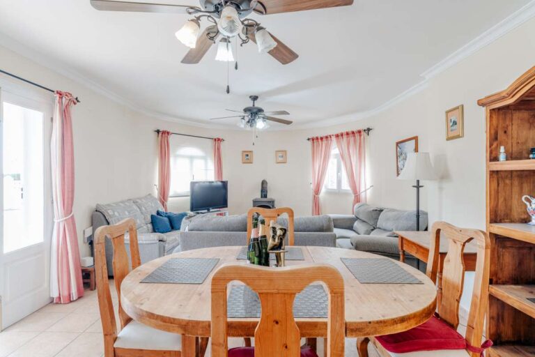 Open living and dining room with sofa seating, dining table and traditional fireplace inside a Mediterranean villa in Calpe.
