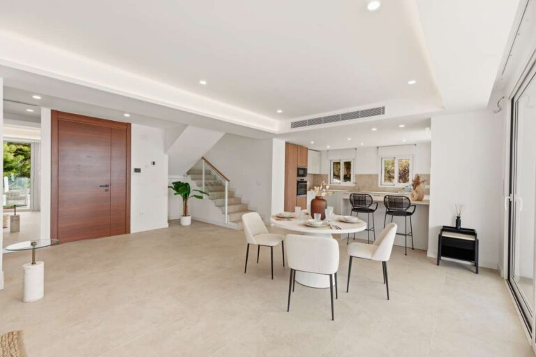 Open-plan dining and living area inside a modern villa in Altea Hills with bright interiors, staircase access and large terrace doors