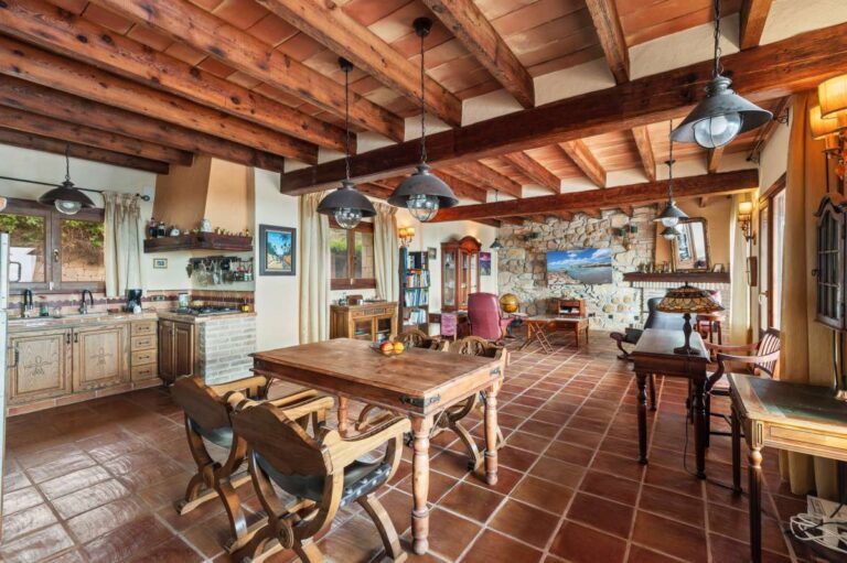 Open-plan kitchen and dining area inside a finca-style villa in Benissa Costa with wooden beams, stone walls, terracotta flooring and rustic kitchen design