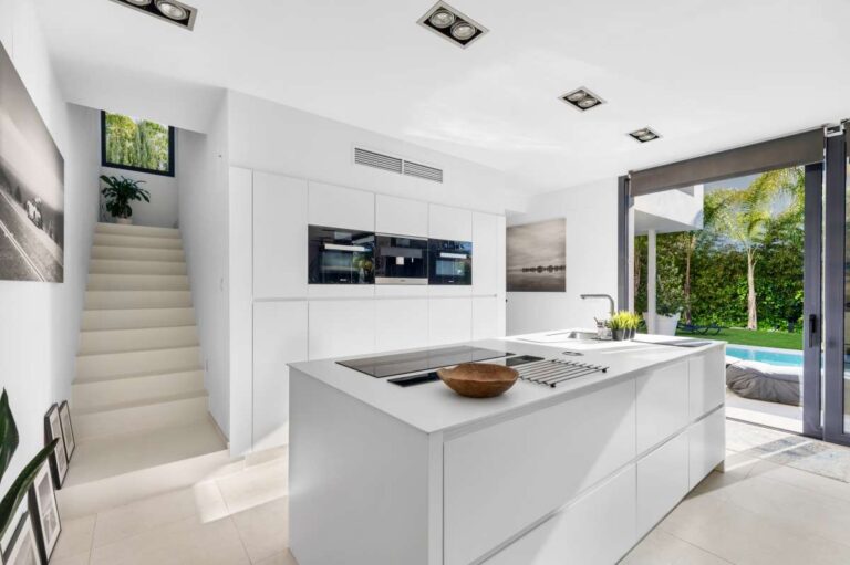 Open-plan kitchen with island, staircase and garden access inside a modern oasis villa near Arenal-Bol Beach in Calpe.