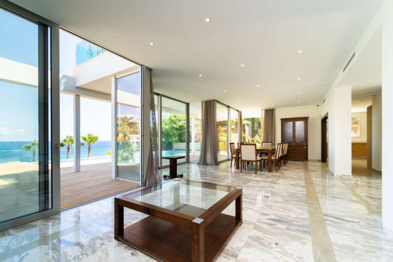 Open-plan living and dining area inside a luxury villa in Calpe with marble flooring, large glass doors and panoramic sea views