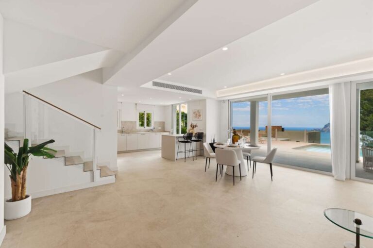 Open-plan living and dining area inside a modern villa in Altea Hills with large windows, sea views, kitchen area and staircase