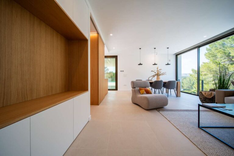 Open-plan living and dining area inside a new-build luxury villa in Moraira with large windows, wood detailing and modern furniture