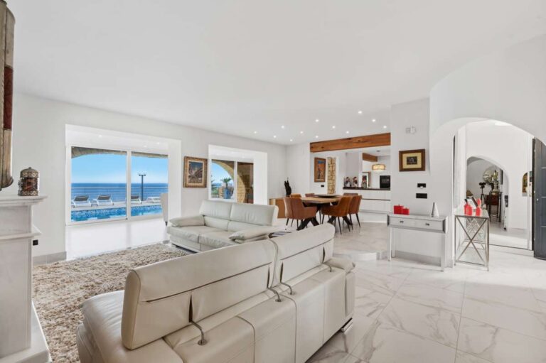 Open-plan living and dining area inside a premium coastal villa on the Benissa Costa with sea views, white seating and bright interior finish