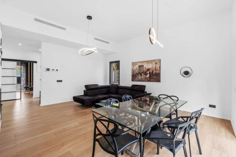 Open-plan living and dining area inside a single-level modern villa in Santa Clara, Altea with wood flooring, high ceiling, large windows and bright interior