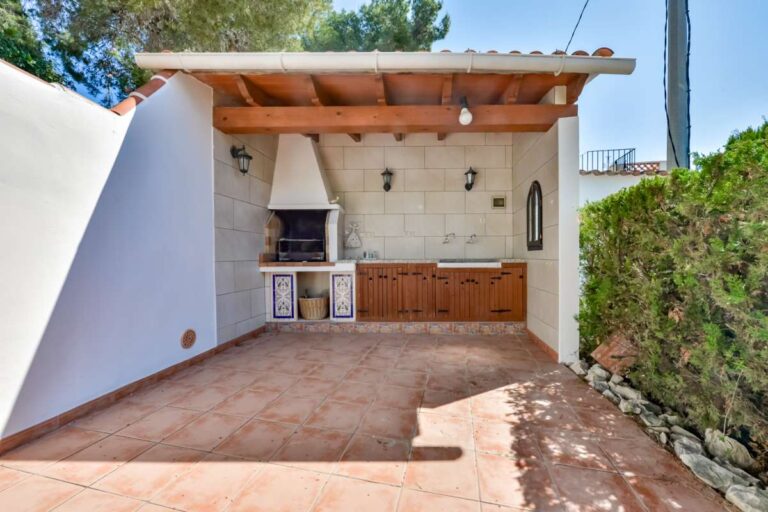 Outdoor barbecue area at a charming Benissa Coast villa with covered terrace, built-in barbecue, storage units and tiled floor