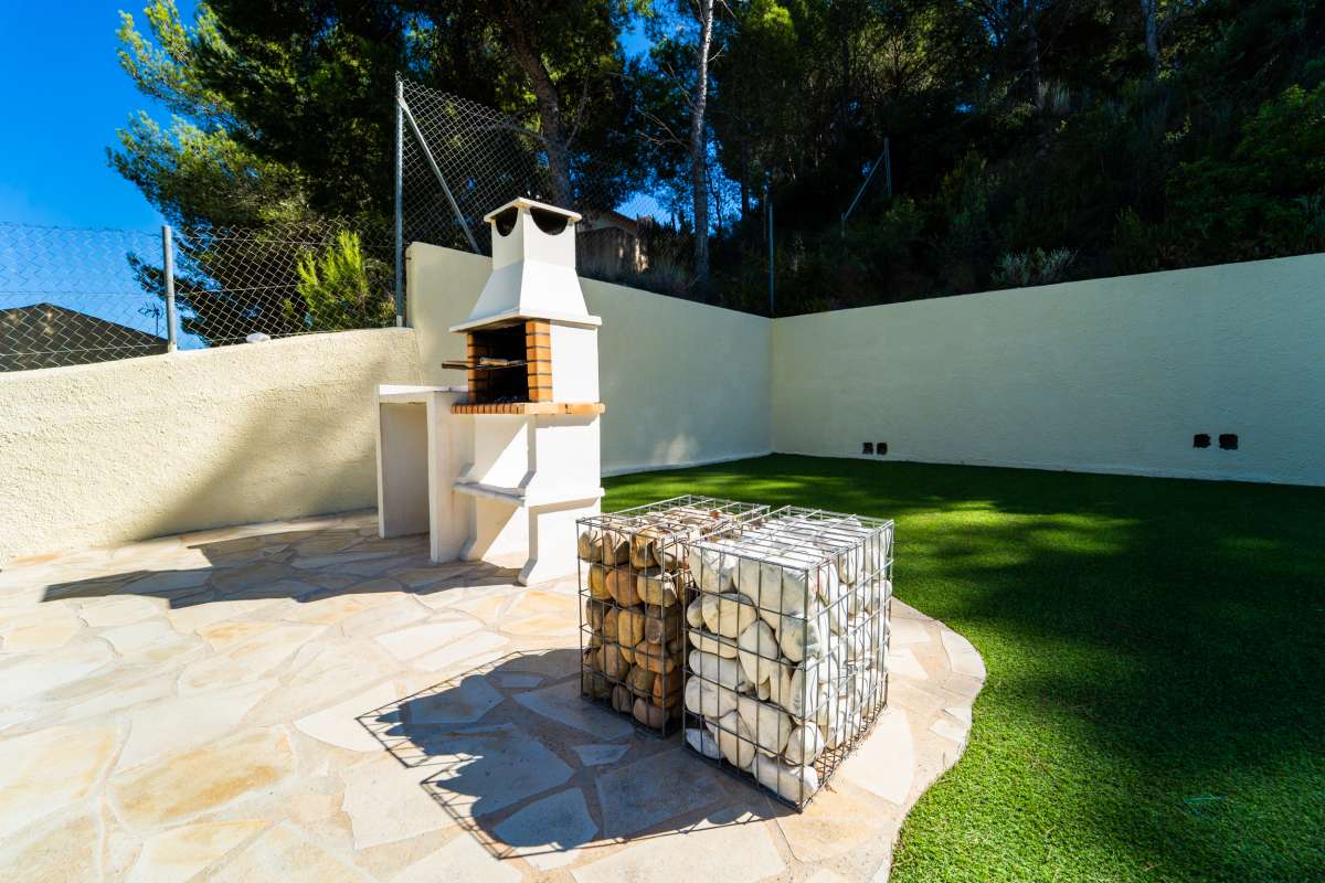 Outdoor barbecue area with stone terrace and garden space at a Mediterranean villa in Calpe.