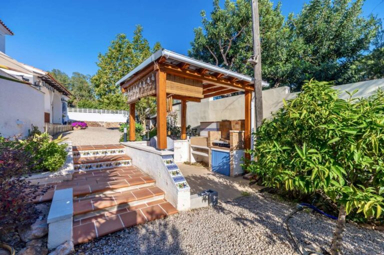 Outdoor BBQ area with covered dining space and garden surroundings at a contemporary villa in Calpe.