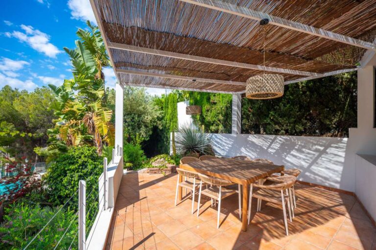 Outdoor dining area at a modern villa in Altea Hills with pergola, wooden table, garden views and shaded terrace space