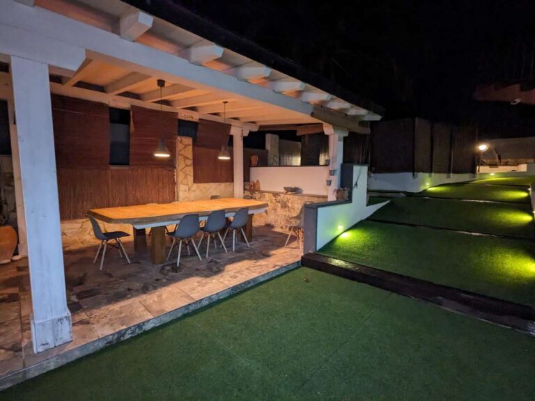 Outdoor dining area at night beside the garden at a refurbished villa with sea views in Canuta, Calpe.