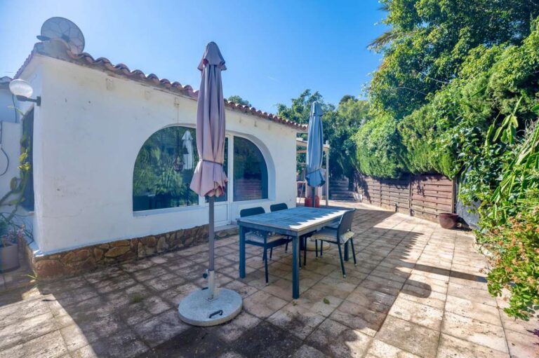 Outdoor dining terrace at a Mediterranean villa in Benissa Costa near Cala Baladrar with arched window, parasols and mature garden surroundings
