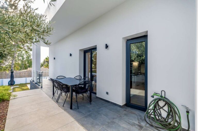Outdoor dining terrace at a single-level modern villa in Santa Clara, Altea with patio seating, garden access, white exterior and private outdoor space