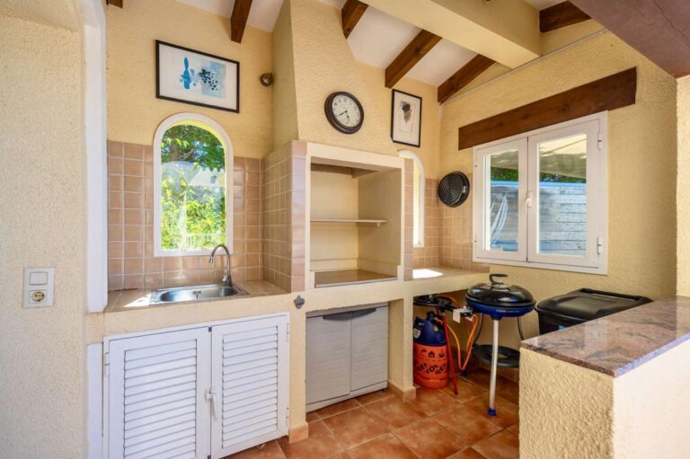 Outdoor kitchen at an elegant Mediterranean villa in Altea Hills with sink, worktop, arched window and covered terrace setting