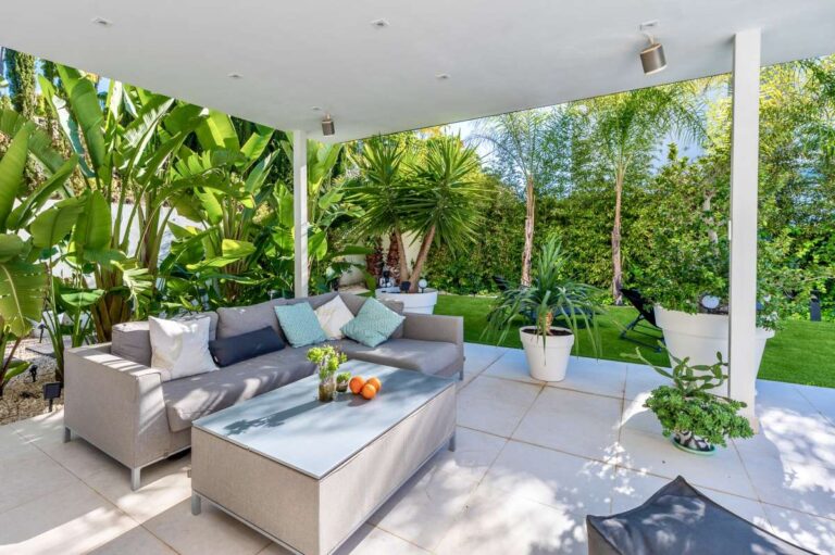 Outdoor lounge terrace with shaded seating and tropical garden at a modern villa near Arenal-Bol Beach in Calpe.