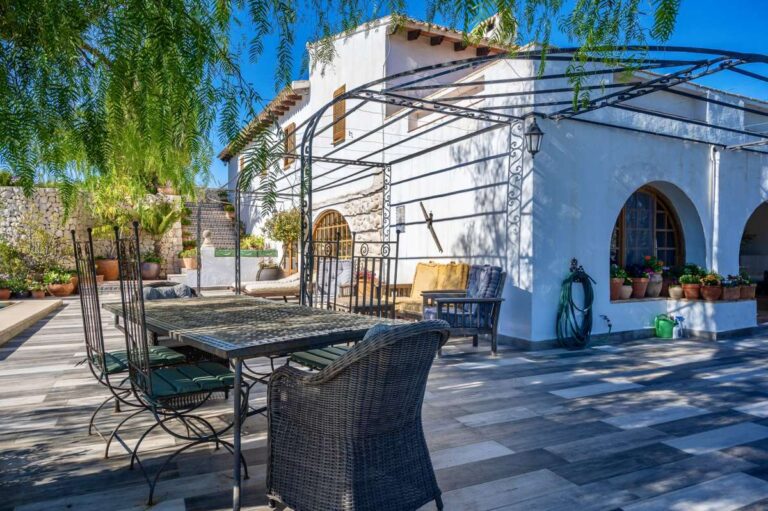 Outdoor seating area at a traditional Spanish finca near Moraira with arched terrace, pergola frame, tiled patio and rustic Mediterranean exterior