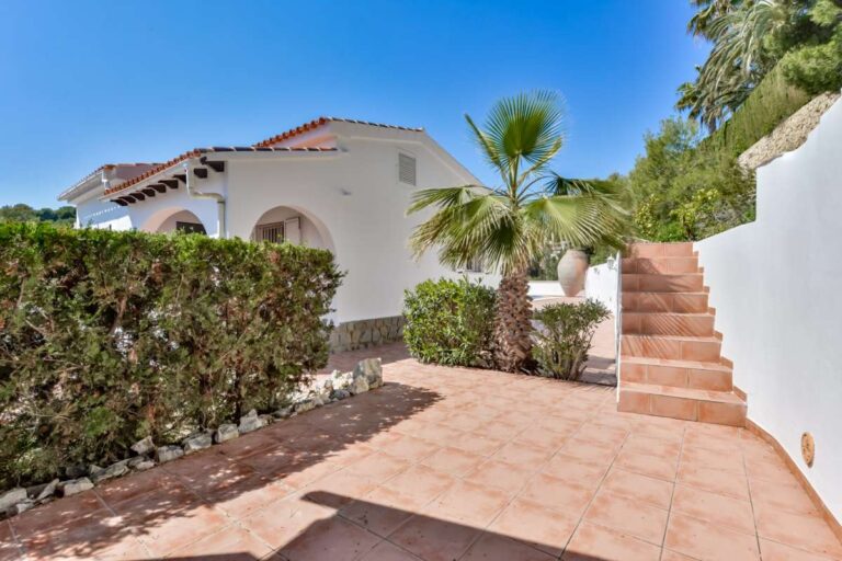 Outdoor terrace at a charming Benissa Coast villa with garden steps, hedging, palm tree and Mediterranean exterior surroundings
