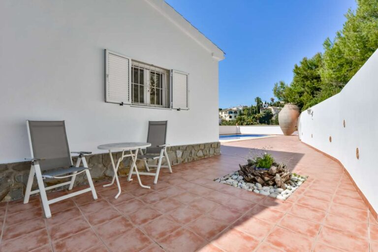 Outdoor terrace at a charming Benissa Coast villa with seating area, tiled floor, white exterior walls and Mediterranean garden details