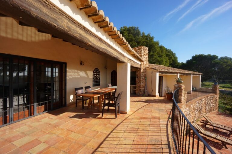 Outdoor terrace at a Mediterranean villa in Calpe with dining area, stone walling, traditional roof detail and garden views