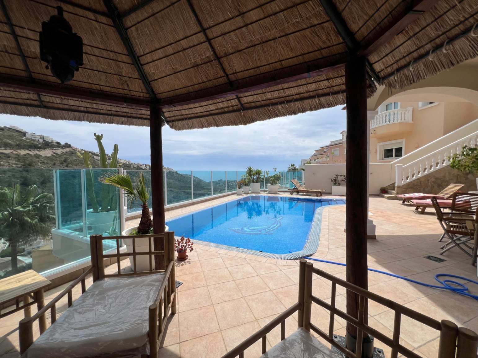 Pergola seating area beside the pool at modern three-level villa in Moraira