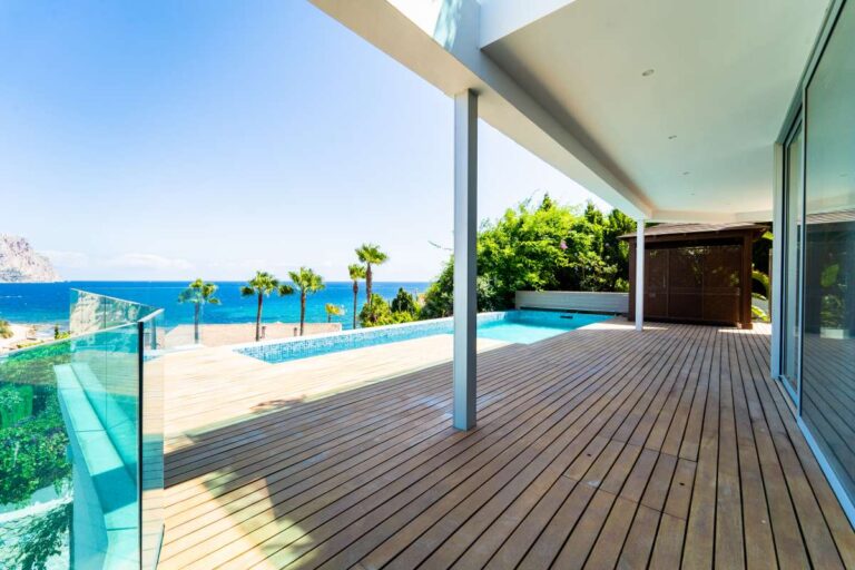 Pool terrace at a luxury villa in Calpe with wooden decking, infinity pool, glass balustrades and Mediterranean Sea views