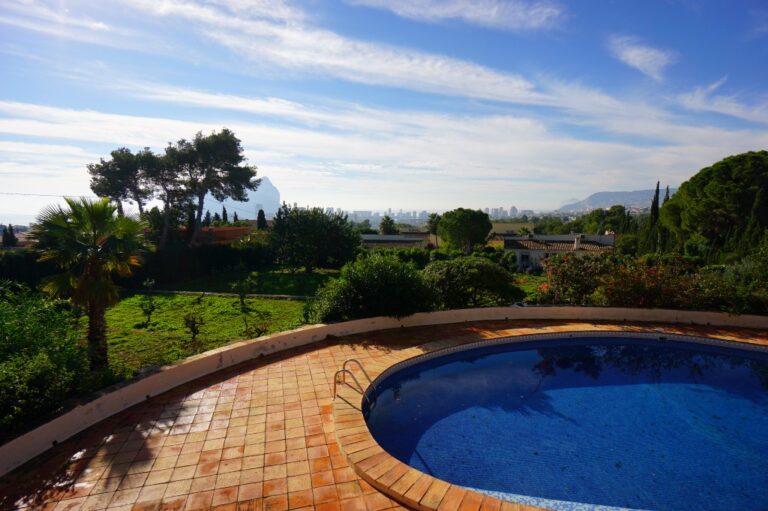 Pool terrace at a Mediterranean villa in Calpe with private swimming pool, mature garden surroundings and open sea views in the distance