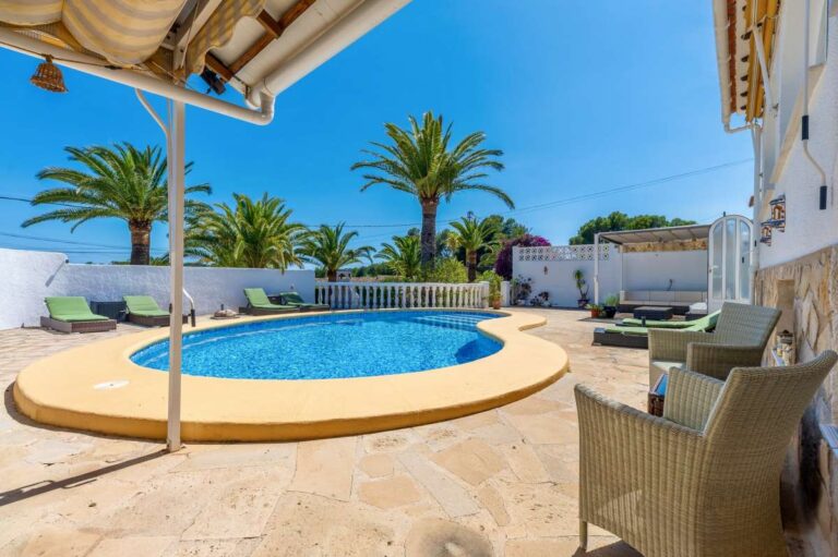 Pool terrace at a renovated single-level villa in Moraira with private swimming pool, outdoor dining area, sun loungers and palm trees