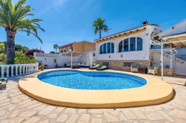 Pool terrace at a renovated single-level villa in Moraira with private swimming pool, palm trees, sun loungers and Mediterranean exterior