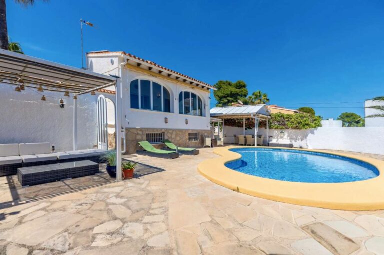Pool terrace at a renovated single-level villa in Moraira with private swimming pool, sun loungers, covered seating area and Mediterranean exterior