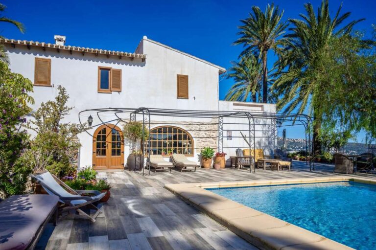 Pool terrace at a traditional Spanish finca near Moraira with private swimming pool, arched windows, sun lounger and Mediterranean planting