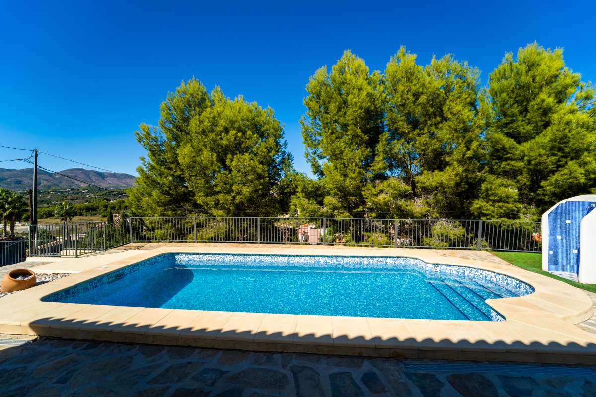 Pool terrace with mountain surroundings, trees and sunny outdoor space at a Mediterranean villa in Calpe.