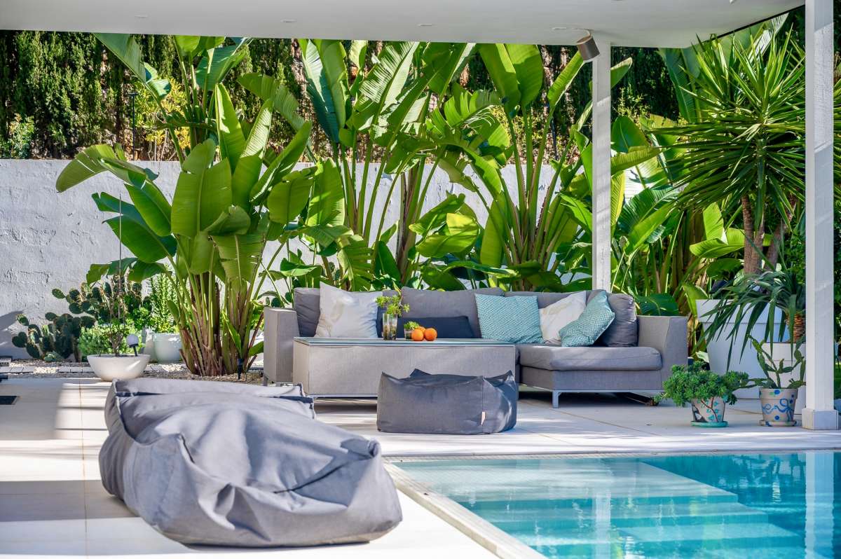 Poolside lounge area with tropical planting at a modern oasis villa near Arenal-Bol Beach in Calpe.