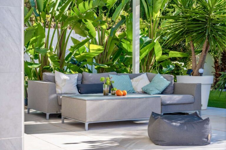 Poolside seating area with tropical planting and shaded lounge space at a modern oasis villa in Calpe.