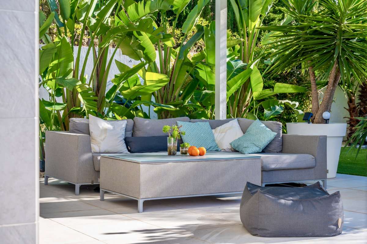 Poolside seating area with tropical planting and shaded lounge space at a modern oasis villa in Calpe.