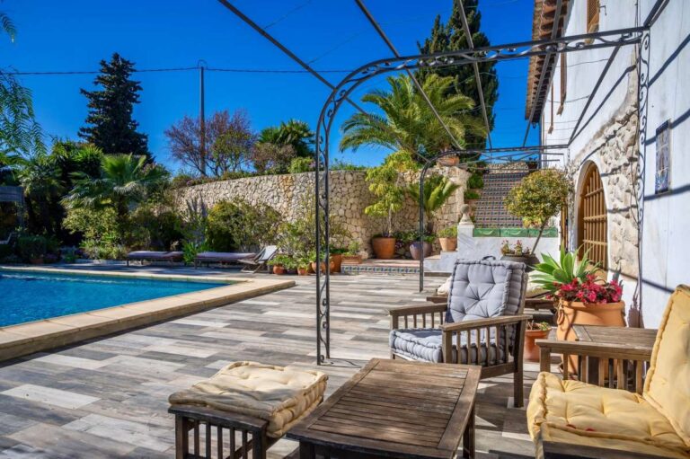 Poolside terrace at a traditional Spanish finca near Moraira with outdoor seating, private swimming pool, arched terrace and Mediterranean garden details