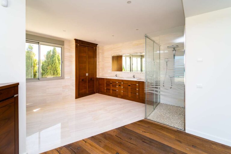Principal bathroom inside a luxury villa in Calpe with walk-in shower, wood cabinetry, large window and bright natural light