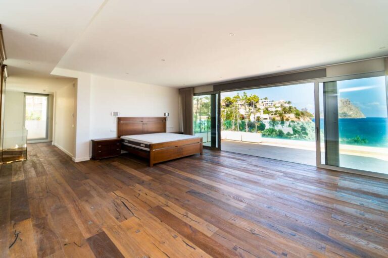 Principal bedroom inside a luxury villa in Calpe with wood flooring, large glass doors, private terrace access and panoramic sea views