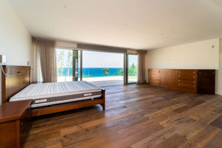 Principal bedroom inside a luxury villa in Calpe with wood flooring, large glass doors, terrace access and panoramic sea views