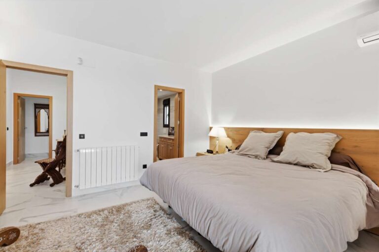 Principal bedroom inside a premium coastal villa on the Benissa Costa with large bed, soft lighting, en-suite access and bright neutral finish