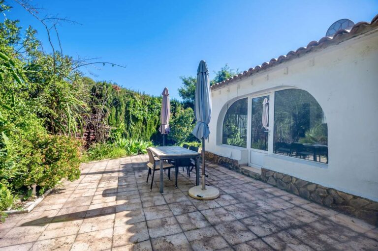 Private garden terrace at a Mediterranean villa in Benissa Costa with outdoor dining space, parasols, stone paving and mature greenery