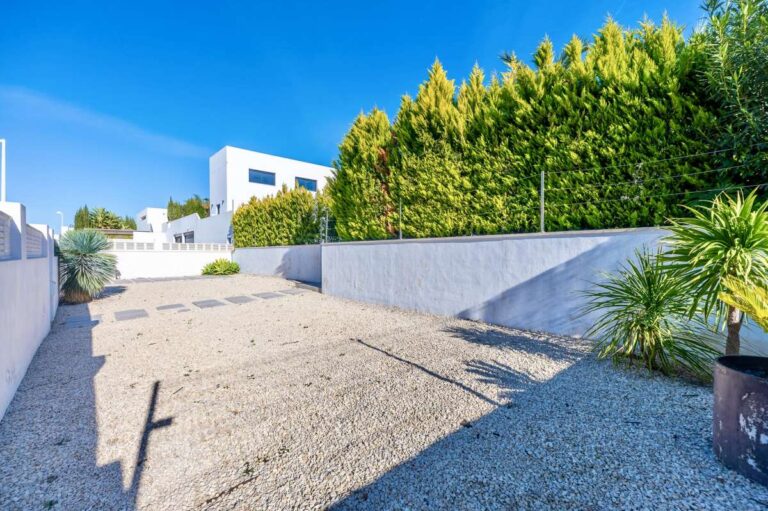 Private gravel parking area with gated access and privacy hedging at a modern oasis villa in Calpe.
