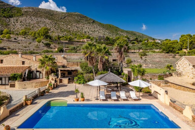 Private pool area at a historic finca in Benissa with sun loungers, parasols, Mediterranean gardens and mountain views