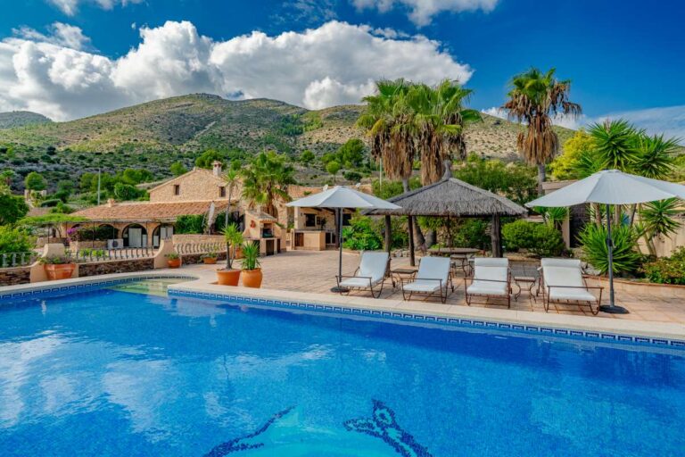Private pool area at a historic luxury finca in Benissa with mountain views, thatched pavilion, sun loungers and Mediterranean gardens